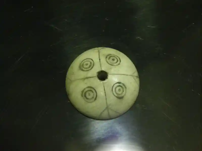 Solar disc with four solar symbols and a cross and a hole in the center